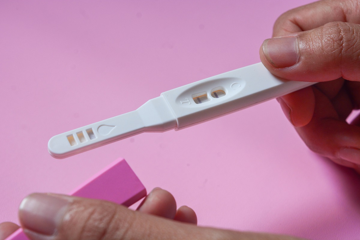 Tehotenský test z moču - žena drží tester v ruke